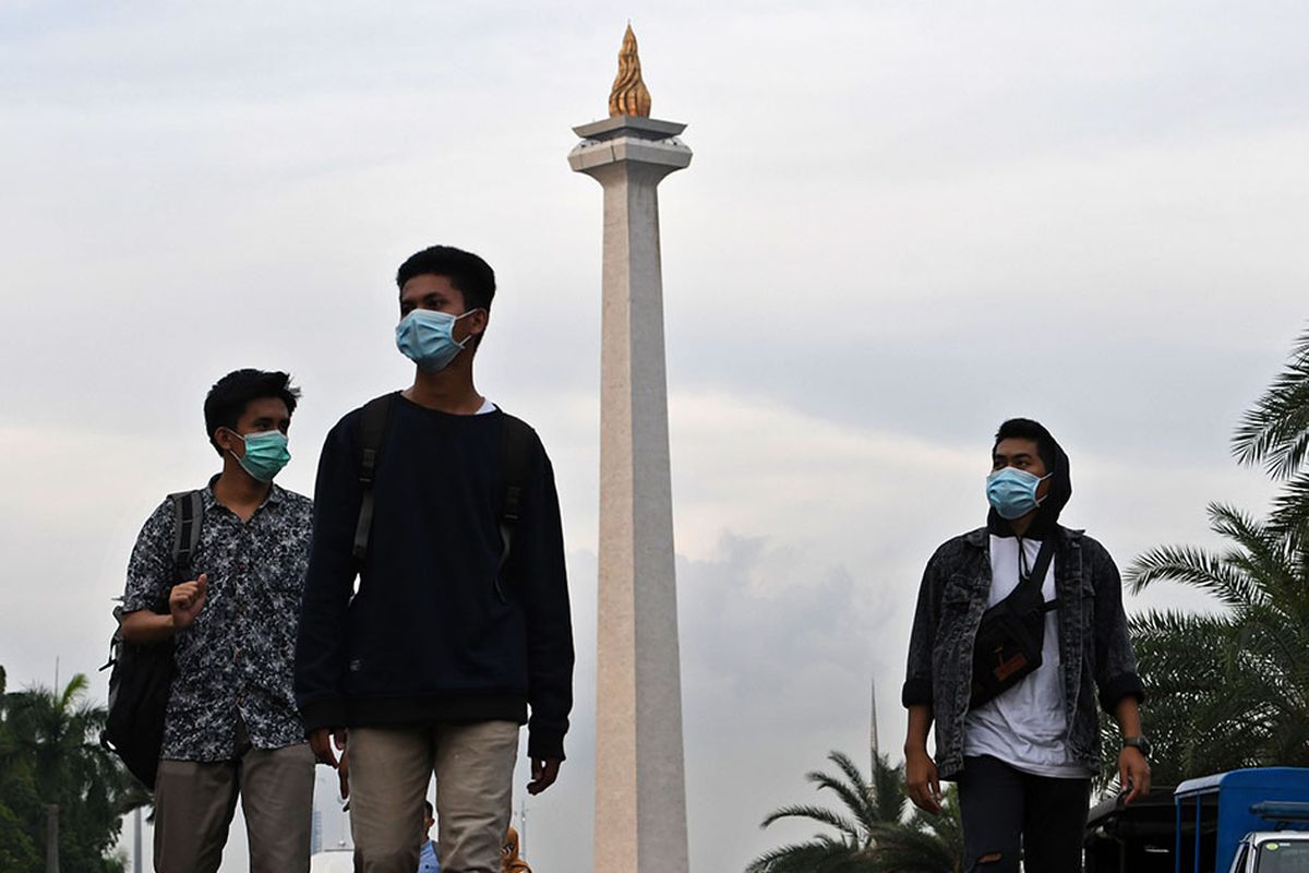 Sejumlah warga dengan menggunakan masker berjalan di kawasan Monumen Nasional,  Jakarta, Rabu (11/3/2020).  