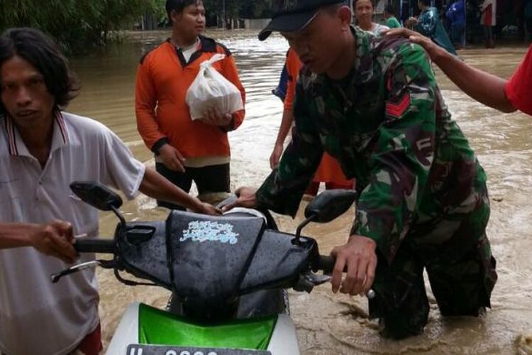 Seorang anggota TNI Kodim 0716 Demak membantu evakuasi kendaraan warga yang terjebak banjir di Desa Sayung,  Kecamatan Sayung,  Kabupaten Demak,  Jateng (16/2/2017)