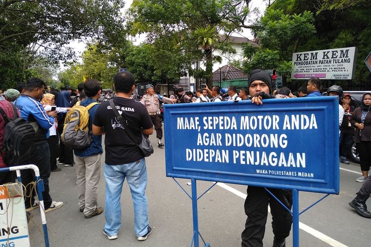 Seorang personel polisi menggeser papan ke tengah jalan untuk menutup akses Jalan HM Said pasca ledakan di Mako Polrestabes Medan, Rabu pagi tadi (13/11/2019).
