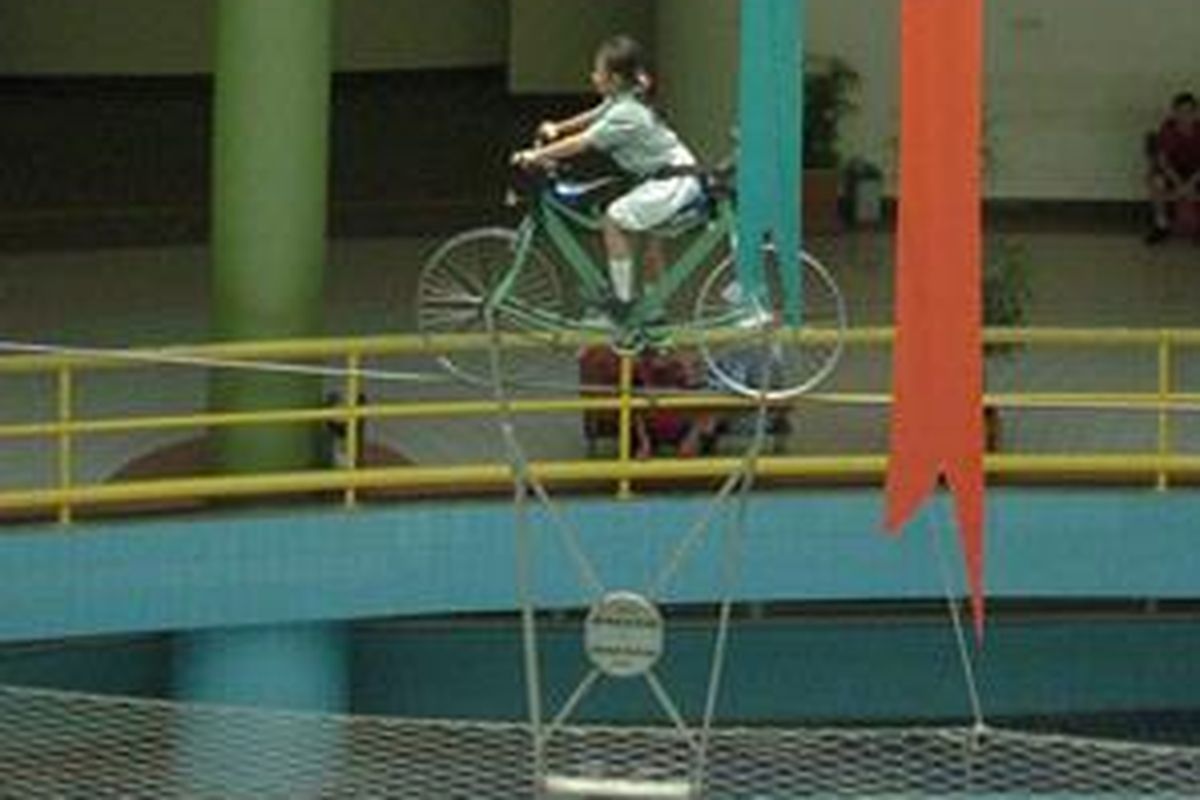 Seorang pelajar mencoba mengendarai sepeda keseimbangan melintasi kawat baja di Pusat Peragaan Ilmu Pengetahuan dan Teknologi, Taman Mini Indonesia Indah Jakarta Timur. PP Iptek menjadi salah satu tempat pembelajaran untuk mempraktikkan berbagai teori ilmiah yang banyak dikunjungi siswa dari berbagai daerah.