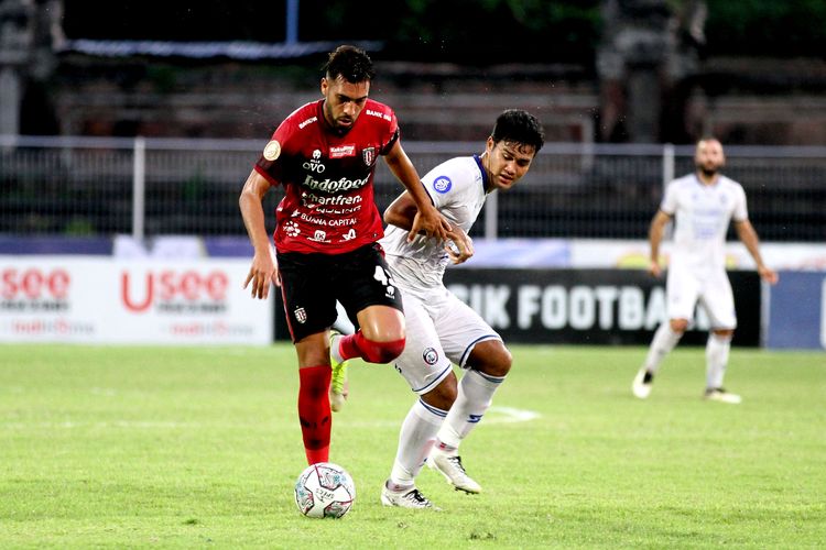 Pemain Bali United Willian Pachecho dijaga ketat pemain Arema FC M Rafli saat pertandingan pekan 31 Liga 1 2021-2022 yang berakhir dengan skor 2-1 di Stadion I Gusti Ngurah Rai Denpasar, Selasa (15/3/2022) sore.