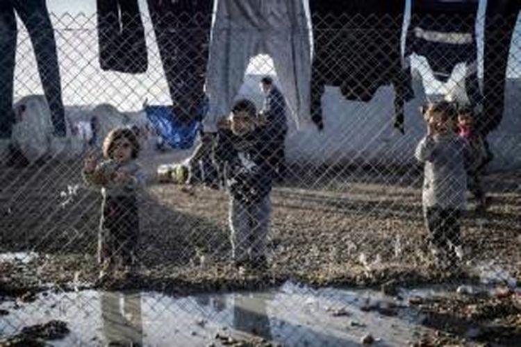 Anak-anak Suriah berdiri di belakang pagar, 1 Februari 2015 di kamp pengungsi Rojava di Sanliurfa.