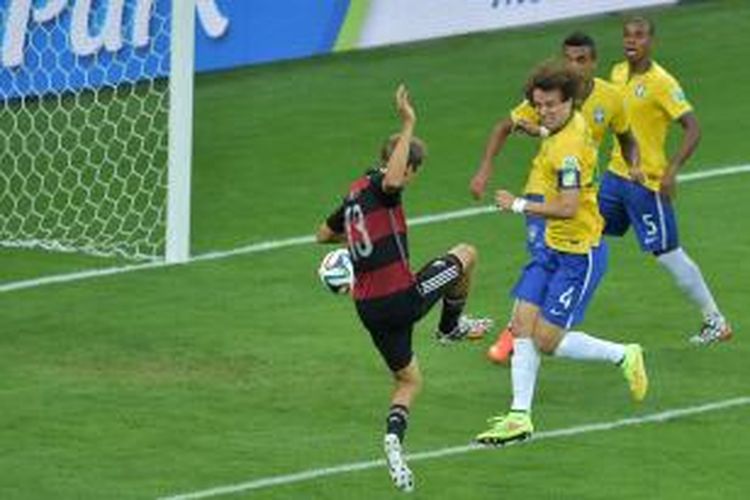 Penyerang Jerman, Thomas Mueller (kiri), melepaskan tembakan yang berujung gol ke gawang Brasil, pada laga semifinal Piala Dunia, di Estadio Mineirao, Belo Horizonte, Selasa (8/7/2014).