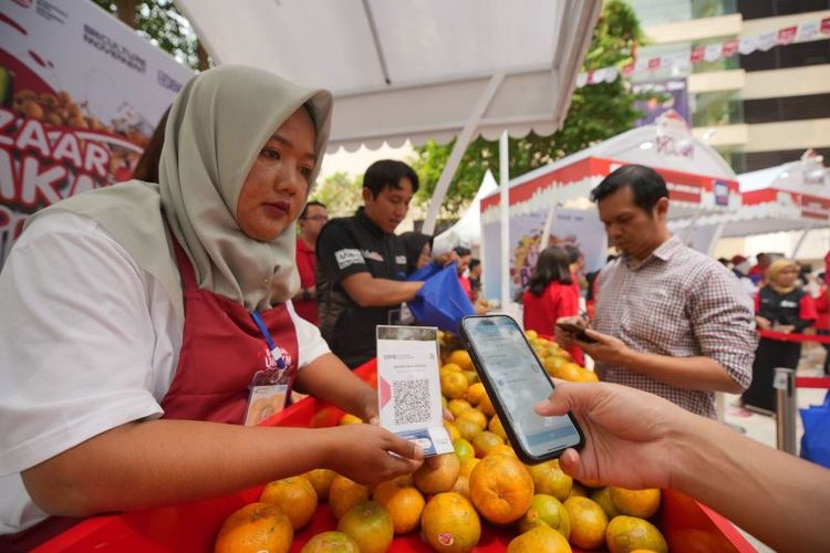 Salah satu anggota Klaster Jeruk Sungai Penuh sedang menunjukkan kode QRIS kepada pembeli yang ingin melakukan transaksi pembelian buah jeruk hasil panen dari klasternya.