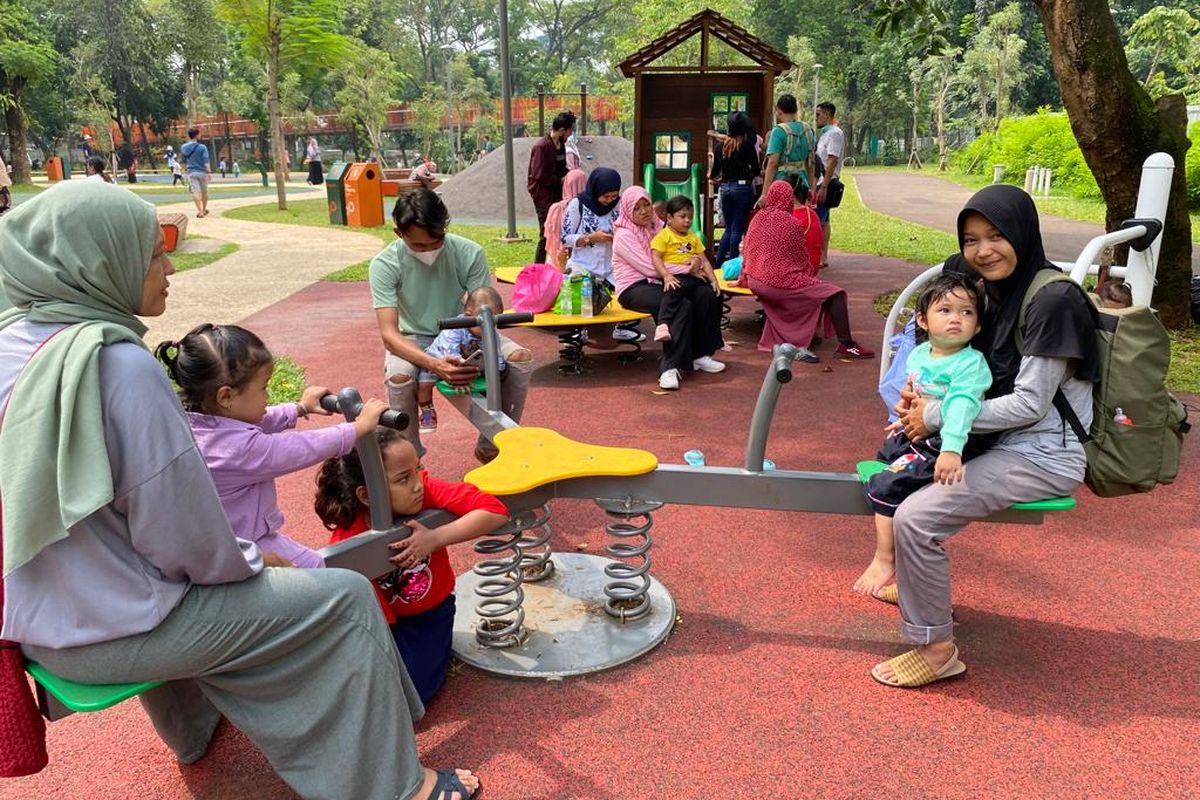 Pengunjung Tebet Eco Park bermain bersama anak-anaknya di area bermain anak.