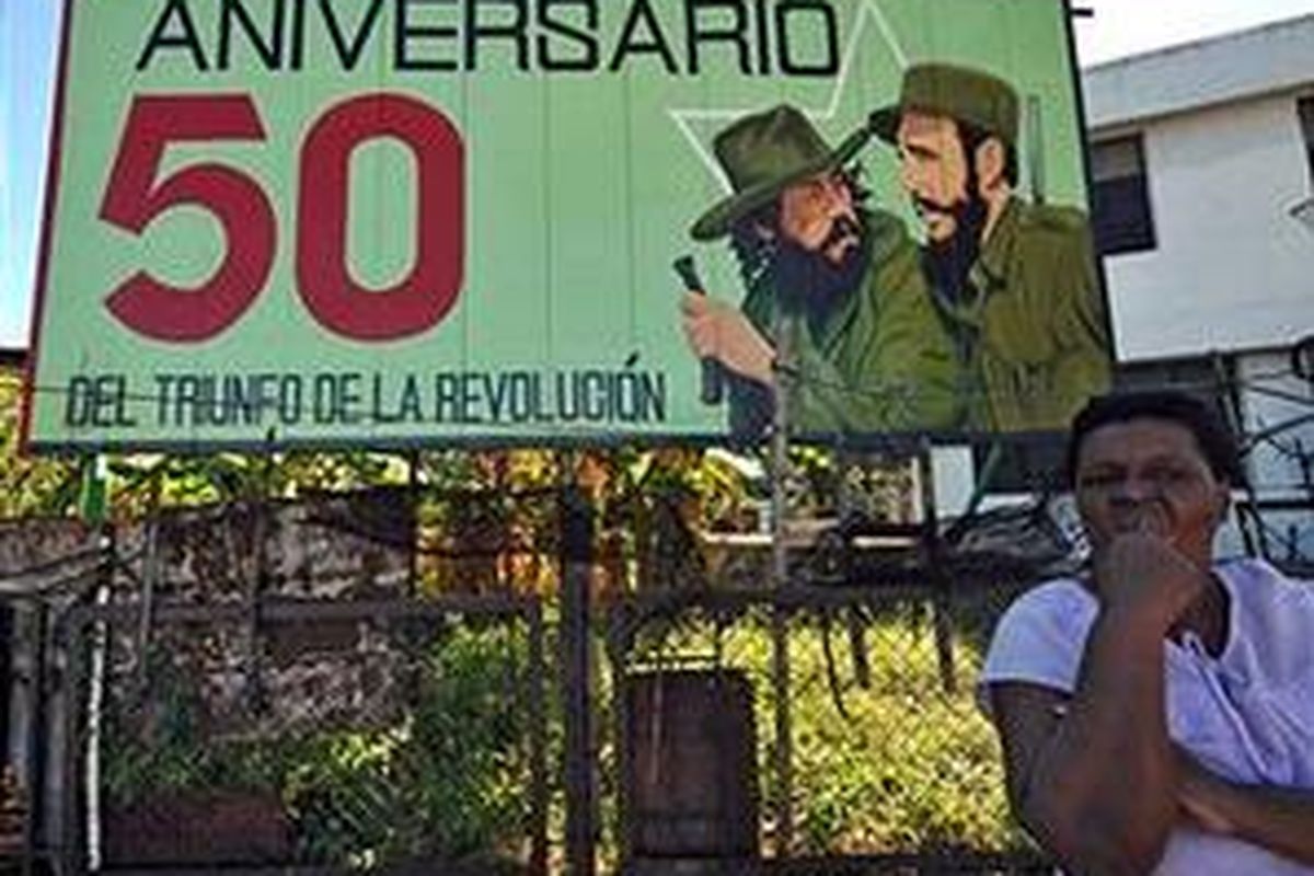 Seorang wanita Kuba berdiri di bawah poster menandai 50 tahun Revolusi, 1 Januari 2009.
