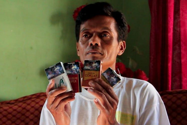 Dadang Mulya menunjukann sejumlah bungkus rokok yang memajang gambar orang yang mirip sekali dengan dirinya, di rumahnya desa Pancalang, Kecamatan Pancalang, Kabupaten Kuningan, Rabu (25 Juli 2018)
