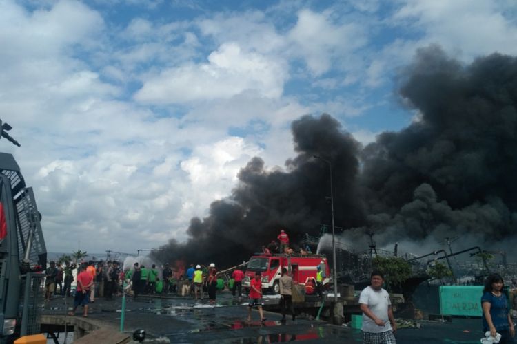 Petugas teus berusaha memadamkan api yang membakar puluhan kapal di Pelabuhan Benoa, Bali, Senin (9/7/2018)