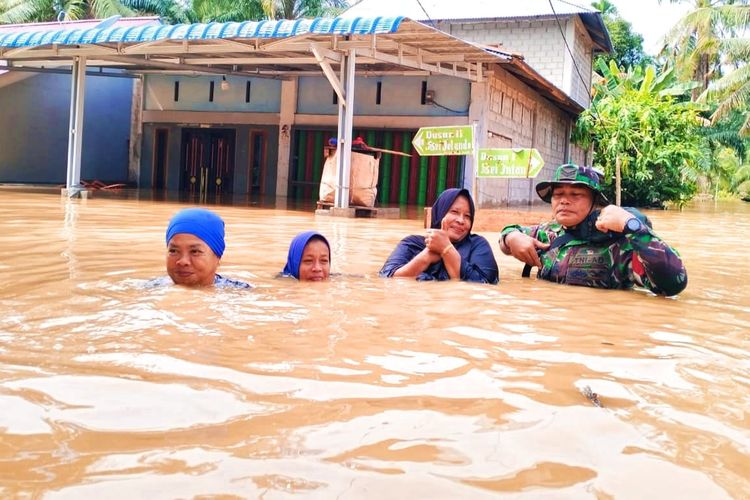 Petugas TNI membantu warga mengarungi banjir untuk pergi mengungsi, di Desa Talikumain, Kecamatan Tambusai, Kabupaten Rokan Hulu, Riau, Senin (1/1/2024).