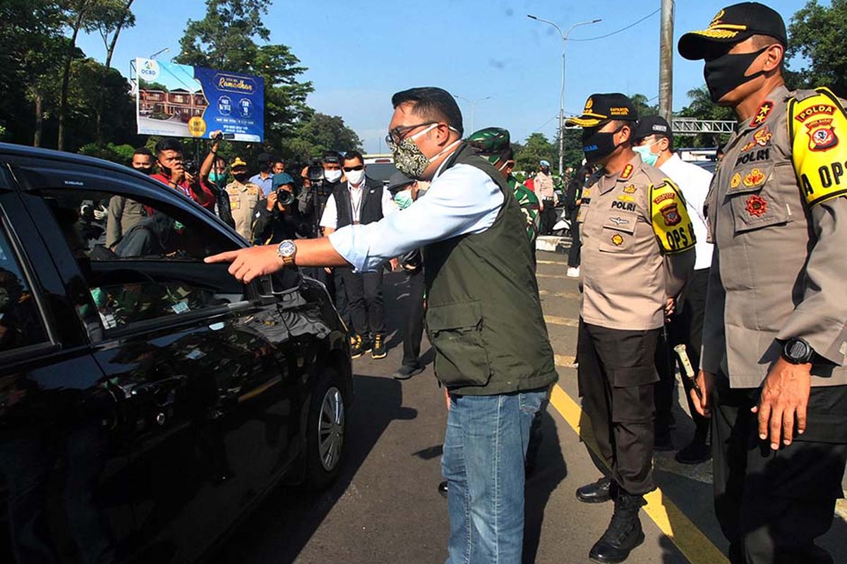 Gubernur Jawa Barat Ridwan Kamil (tengah) bersama Kapolda Jabar Irjen Pol Rudy Sufahriadi (kanan) berbincang dengan pengendara mobil saat pemantauan pelaksanaan Pembatasan Sosial Berskala Besar (PSBB) hari pertama di pos check point pintu keluar Tol Jagorawi, Kota Bogor, Jawa Barat, Rabu (15/4/2020). Gubernur Jawa Barat menilai pelaksanaan PSBB di Kota Bogor berjalan baik terlihat dari penurunan jumlah kendaraan yang masuk Kota Bogor lewat pintu Tol Jagorawi mencapai 50 persen.