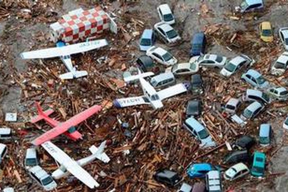 Mobil dan pesawat terbang disapu gelombang tsunami pascagempa di Bandara Sendai, utara Jepang, Jumat (11/3/2011).