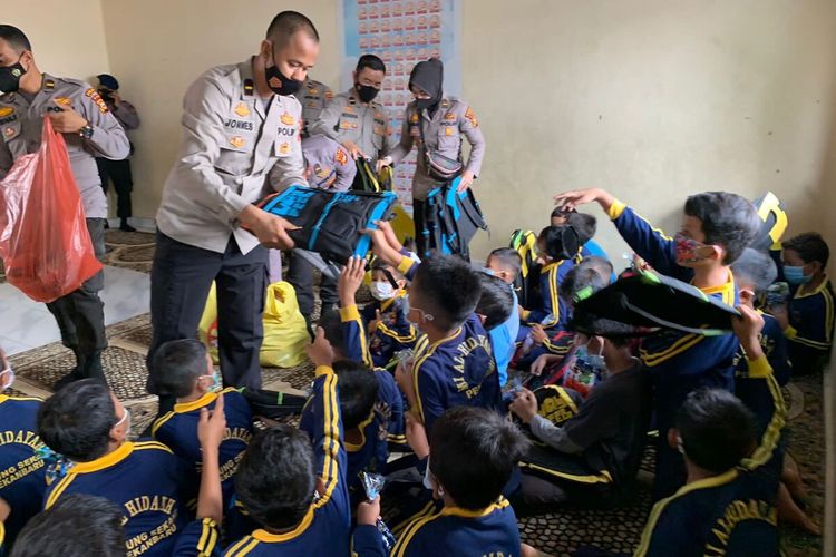 Anggota polisi membagikan perlengkapan sekolah kepada anak-anak sekolah di Yayasan Al Hidayah di Kota Pekanbaru, Riau, Kamis (28/10/2021).