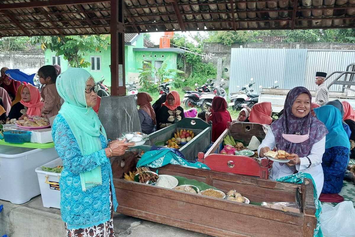 Salah satu warga Titik Marwati (58) saat mengambil makanan dari dalam jodhang untuk dibagikan kepada warga masyarakat Padukuhan Saren, Kalurahan Wedomartani, Kapanewon Ngemplak, Kabupaten Sleman yang hadir mengikuti acara Nyadran Pasar.