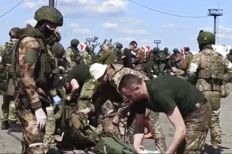 Dalam foto yang diambil dari video yang dirilis oleh Kementerian Pertahanan Rusia pada hari Jumat, 20 Mei 2022, prajurit Rusia menggeledah prajurit Ukraina setelah mereka meninggalkan pabrik baja Azovstal yang terkepung di Mariupol, di wilayah di bawah pemerintahan Republik Rakyat Donetsk, Ukraina timur. 