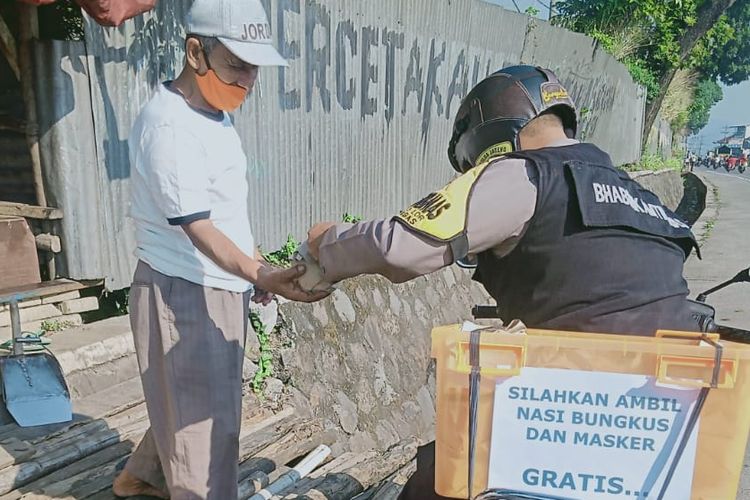 Bhabinkamtibmas Bergas Lor Polres Semarang  Bripka Kak Agus Hermanto membagikan nasi bungkus untuk warga terdampak pandemi.