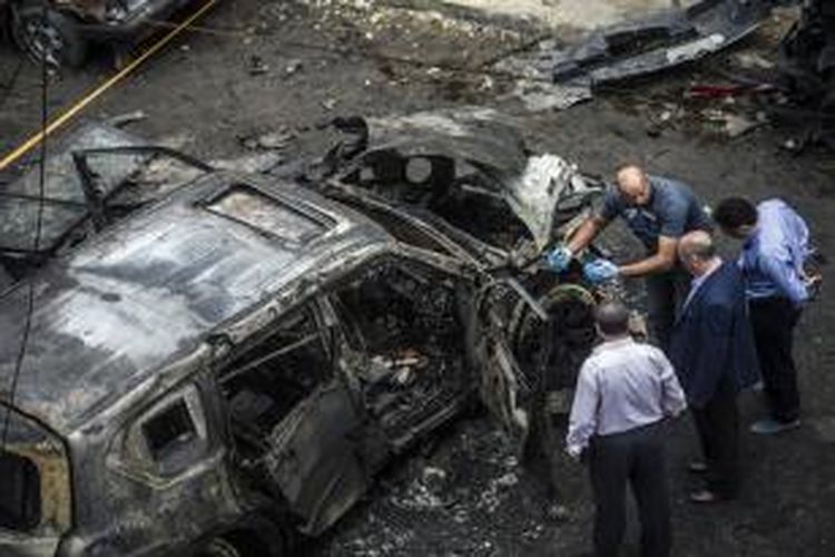 Petugas forensik kepolisian Mesir tengah memeriksa sebuah bangkai mobil yang hancur saat bom meledak dan menghantam iring-iringan kendaraan jaksa Hisham Barakat, Senin (29/6/2015).