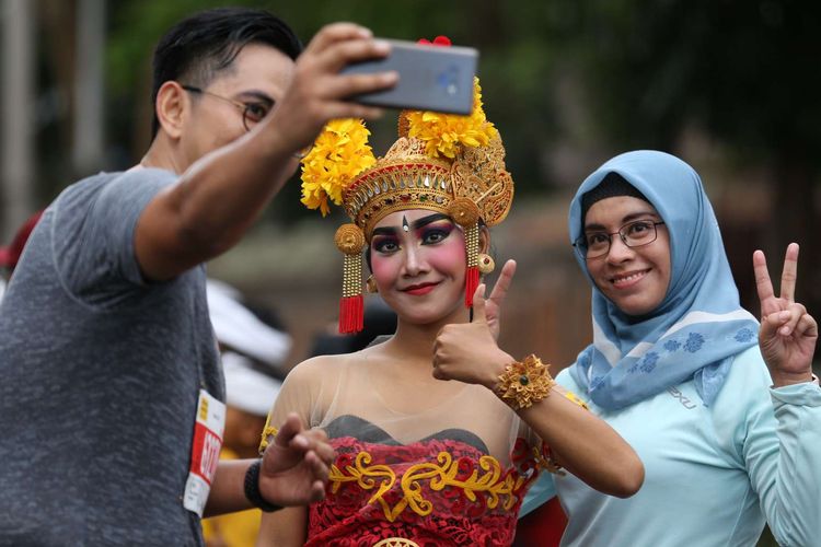 Tak hanya menikmati lomba lari di ajang Maybank Marathon Bali 2019, Minggu (8/9/2019), para peserta pun menyempatkan diri berpose dengan warga setempat yang khusus berdandan dengan baju adat.