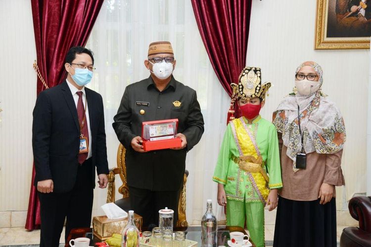 Kepala Perwakilan Bank Indonesia Provinsi Gorontalo, Budi Widihartanto saat menyerahkan uang Peringatan Kemerdekaan pecahan 75000 kepada Gubernur Gorontalo Rusli habibie. Budi Widihartanto juga mengenalkan Aditya Perpatih, anak Gorontalo yang fotonya mengenakan baju adat menghiasi uang tersebut.