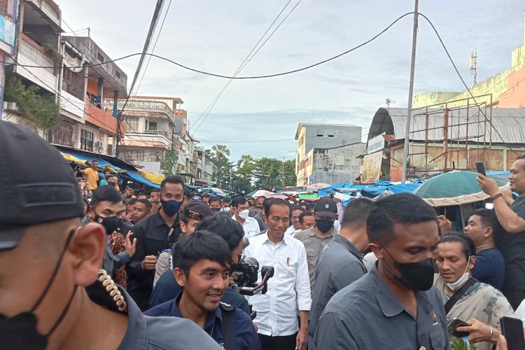 Presiden Jokowi yang membagikan baju kaos hitam bergambar dirinya ke masyarakat di Pasar Terong Makassar