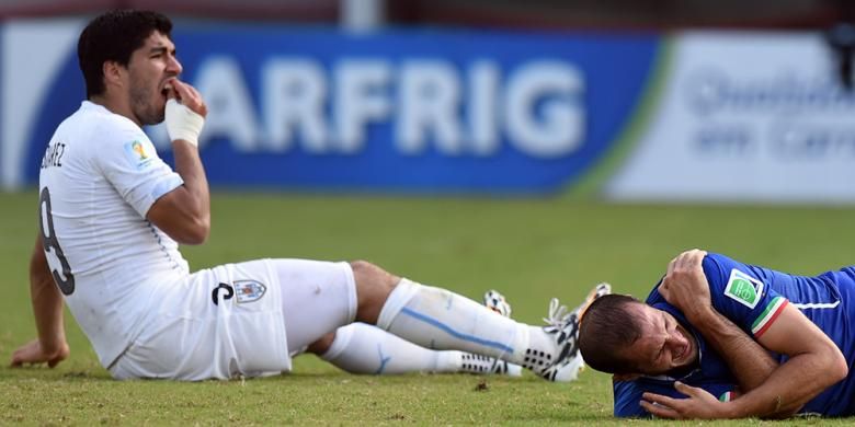 Penyerang Uruguay Luis Suarez (kiri) bereaksi setelah menggigit bek Italia Giorgio Chiellini dalam laga Grup D Piala Dunia di Dunas Arena di Natal, Rabu (25/6/2014). Uruguay menang 1-0. 