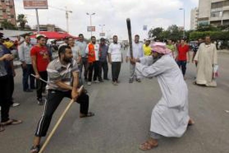 Pendukung Presiden Mesir Muhammad Mursi berlatih menggunakan tongkat di luar masjid Rabia el-Adawiya dengan Istana Presiden di Kairo, Mesir, 2 Juli 2013.