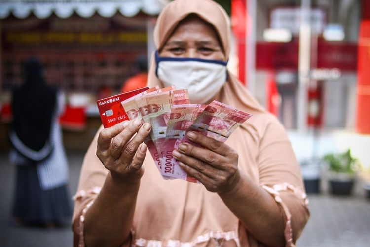Warga menunjukkan uang bantuan sosial tunai atau BST usai mengambil di ATM Bank DKI, Jakarta, Selasa (20/7/2021). Pemprov DKI menyiapkan anggaran Rp604 miliar untuk bantuan sosial tunai atau BST kepada 1 juta Kepala Keluarga (KK) penerima manfaat selama PPKM darurat. Nilai BST kali ini mencapai Rp600.000 per KK dari hasil rapelan penyaluran tahap 5 dan 6 yang sempat tertunda pada Mei-Juni 2021 lalu. ANTARA FOTO/Rivan Awal Lingga/foc.
