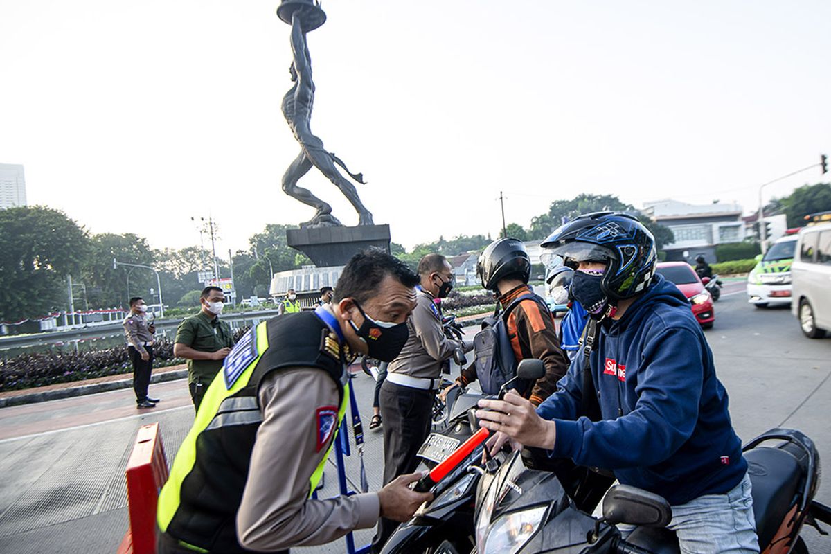 Anggota Polisi memeriksa identitas pengendara sepeda motor saat berlangsungnya Pemberlakuan Pembatasan Kegiatan Masyarakat (PPKM) Darurat di kawasan Bundaran Senayan, Jakarta, Sabtu (3/7/2021). Petugas akan memberikan akses untuk melintas di titik penyekatan PPKM Darurat di 63 titik di wilayah Jadetabek yang berlaku dari 3 - 20 Juli 2021 hanya yang masuk kategori sektor-sektor esensial. ANTARA FOTO/M Risyal Hidayat/hp.