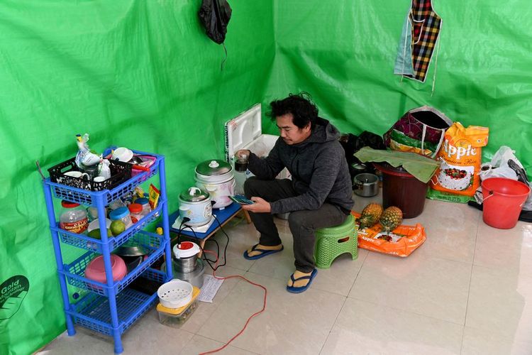 Aung Nay Myo, penyelenggara protes dan penulis satir dari Myanmar, minum teh sambil melihat foto ayahnya di ponselnya di dalam tempat penampungan sementara di sebuah lokasi yang dirahasiakan di sebuah kota di negara yang berbatasan dengan Myanmar, Kamis (27/1/2022). 