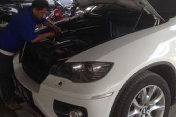 Salah satu mekanik bengkel Sinar Sakti Motor sedang memperbaiki mobil BMW milik konsumennya.