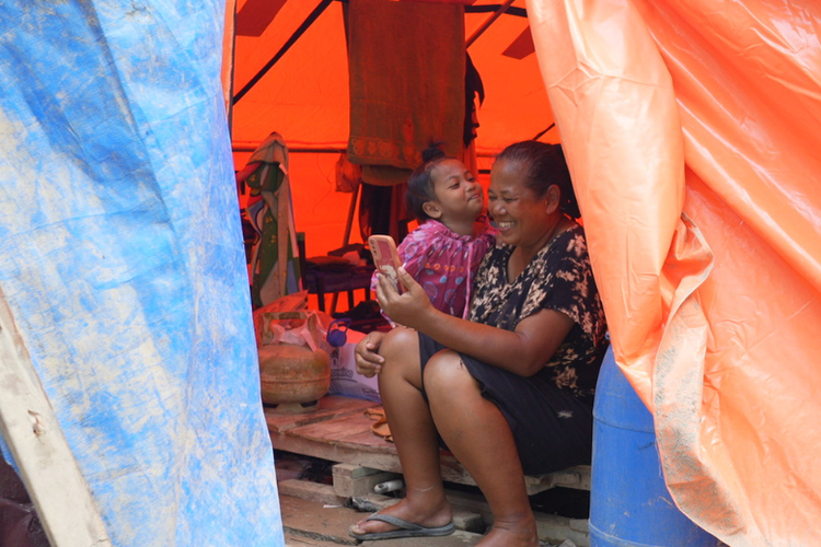 Seorang ibu dan anak memanfaatkan layanan telekomunikasi pascabencana di Sumatera. 