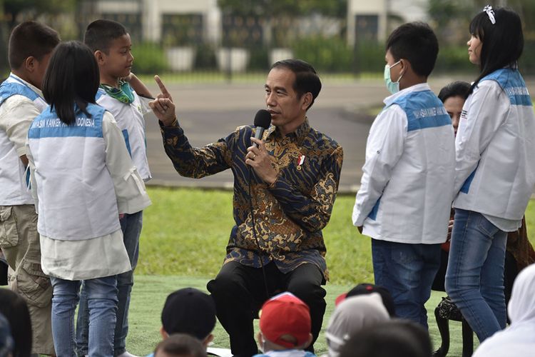 Presiden Joko Widodo (tengah) memberikan kuis untuk anak-anak penderita kanker pendampingan Yayasan Kanker Anak Indonesia saat silaturahmi di halaman belakang Istana Bogor, Jawa Barat, Jumat (6/4/2018). Yayasan Kanker Anak Indonesia dalam kesempatan tersebut meminta regulasi impor obat kanker dipermudah dan bea masuk ditiadakan.