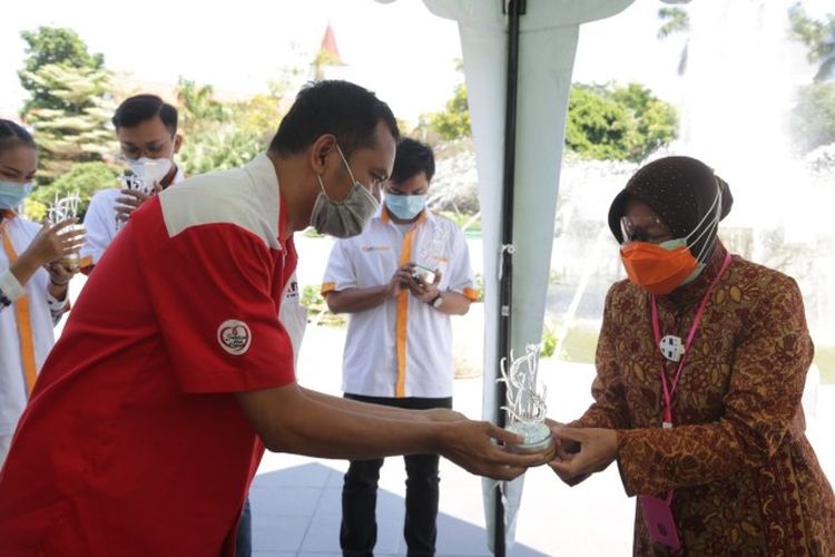 Wali Kota Surabaya Tri Rismaharini memberikan kenang-kenangan berupa cinderamata kepada petugas mobil laboratorium PCR BNPB di Dapur Umum Balai Kota Surabaya, Rabu (17/6/2020).