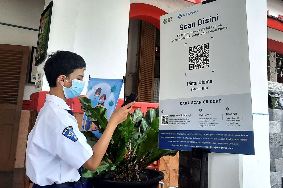 Seorang siswa SMPN 1 Kota Blitar memindai bar code dari aplikasi PeduliLindungi di smartphone miliknya, Senin (18/10/2021)