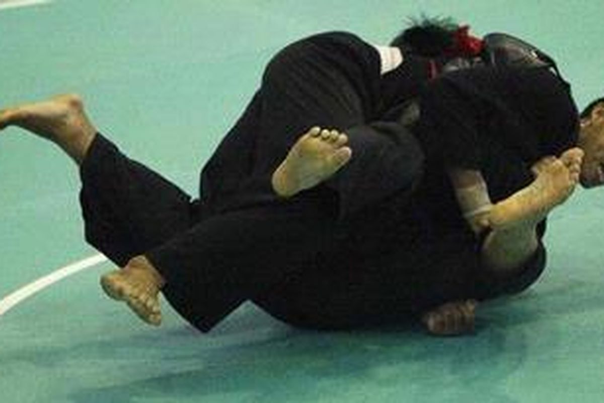 Pesilat Heriono dari Indonesia (atas) membanting pesilat Le Dang Minh dari Vietnam dalam kelas I (85 - 90 kg) kategori tanding putra Kejuaraan Dunia Pencak Silat XIII-2010 di Padepokan Pencak Silat, Jakarta, Rabu (15/12/2010). Heriono kalah angka 56 - 88. 