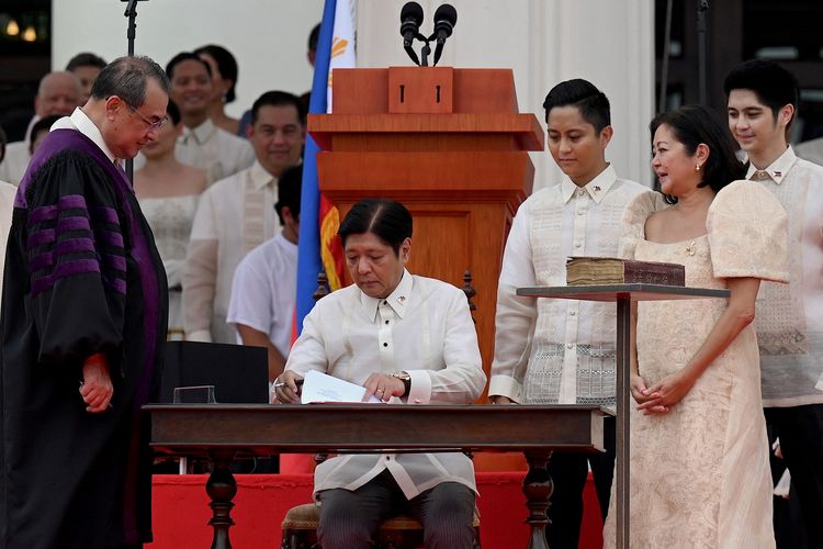 Members of his family (right) look on as new Philippine President Ferdinand Marcos Jr. (seated center) is sworn in as the country's new leader, during his inauguration ceremony at the National Museum in Manila on June 30, 2022. (Photo by JAM STA ROSA / AFP)