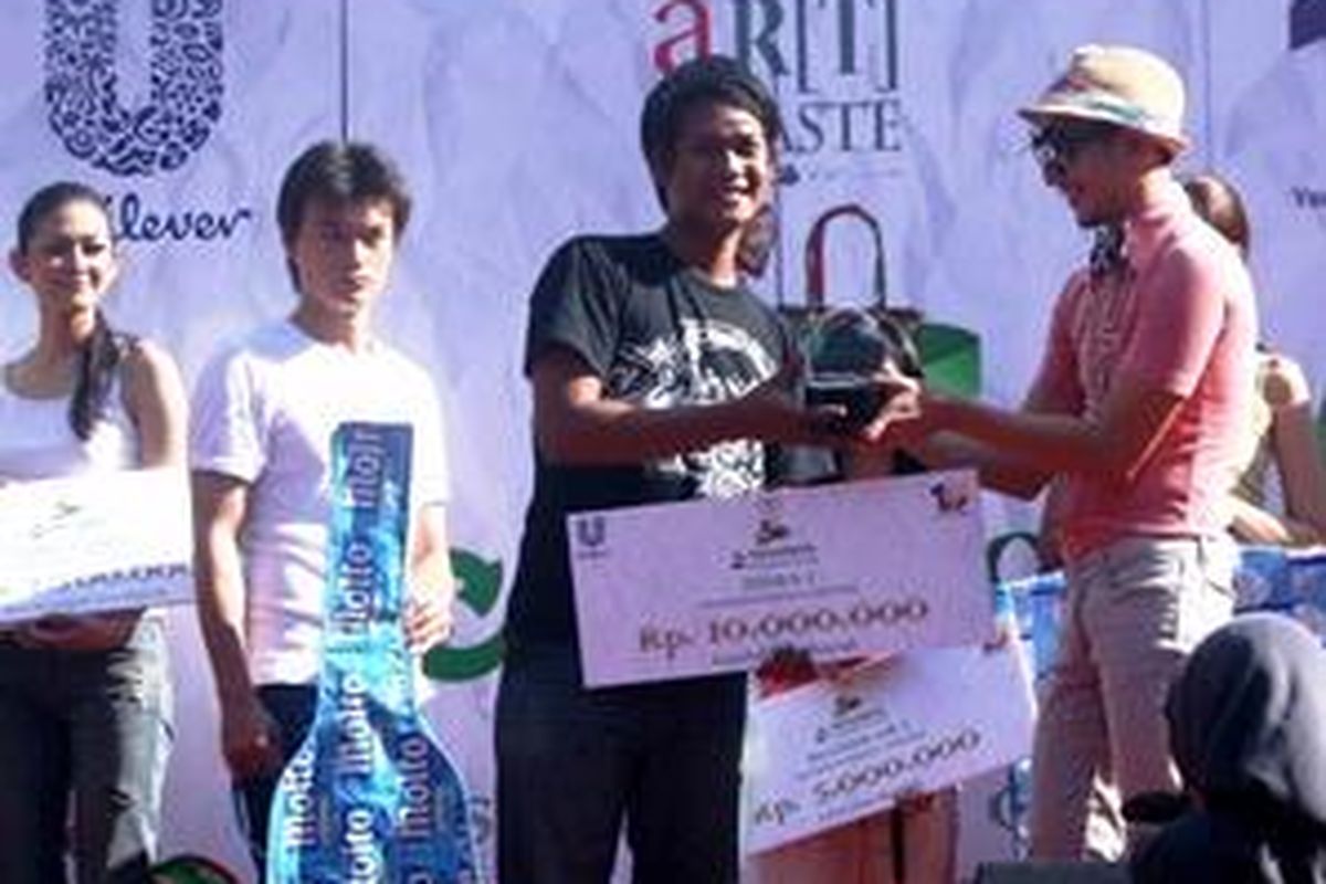 Ichwan Thoha (kanan), salah satu juri, memberikan hadiah untuk pemenang pertama Trashion Design Contest 2010: Dimas Tri Anggodo dari STIKOM Interstudi.
