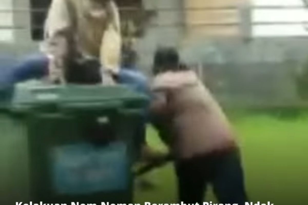 Potongan gambar video sekelompok pemuda berambut pirang yang mendorong dan merobohkan bak sampah.