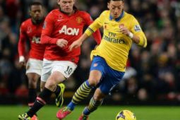 Striker Manchester United, Wayne Rooney (tengah), berusaha merebut bola dari kaki gelandang Arsenal, Mesut Oezil (kanan), dalam laga di Stadion Old Trafford, Manchester, Minggu (10/11/2013).