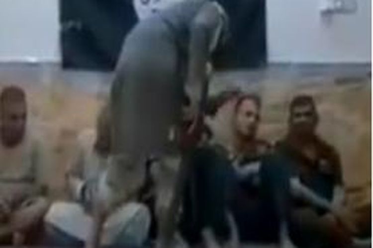 Dalam foto yang diambil dari video yang diunggah ke situs YouTube ini memperlihatkan seorang anggota ISIS tengah menghajar kawan-kawannya yang ketahuan tengah mengisap rokok.