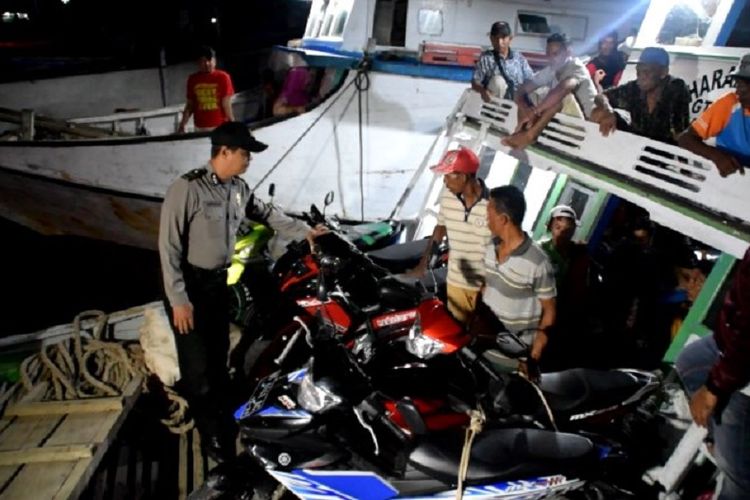 Akibat melebihi kapasitas, petugas pelabuhan Kota Baubau, Sulawesi Tenggara menurunkan sebagian penumpang dan muatan dari atas kapal kayu penumpang.