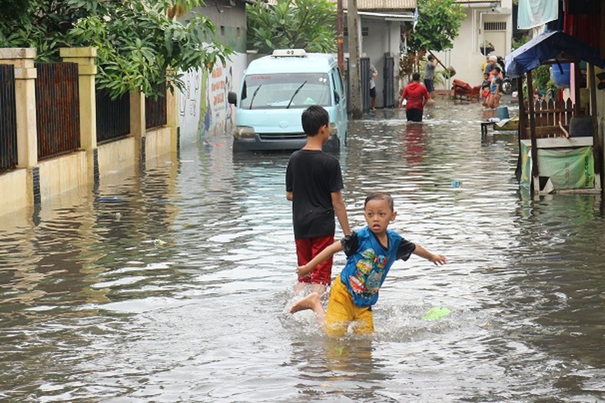 Anak-anak memanfaatkan air banjir untuk bermain di sekitaran Kali Sekretaris, Kebon Jeruk, Jakarta Barat, Rabu (1/1/2020).