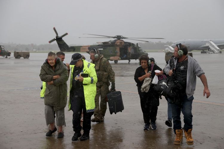 Foto selebaran yang diambil dan dirilis oleh Departemen Pertahanan Australia pada 28 Februari 2022 ini menunjukkan seorang awak pesawat Angkatan Darat Australia dan petugas Layanan Kepolisian Queensland membantu penduduk yang diselamatkan oleh awak helikopter MRH-90 Taipan Angkatan Darat Australia dari Sekolah Penerbangan Angkatan Darat di tengah-tengah banjir di tenggara 