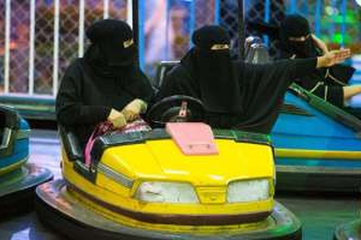 Perempuan Arab Saudi dengan pakaian hitap menutupi sekujur tubuh, sedang bermain bombom car.