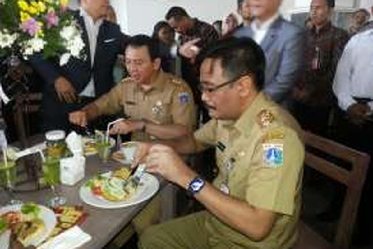 Gubernur DKI Jakarta Basuki Tjahaja Purnama dan wakilnya, Djarot Saiful Hidayat menjajal burger yang dihidangkan saat peresmian kafe JakBistro di Balai Kota, Senin (17/10/2016). 