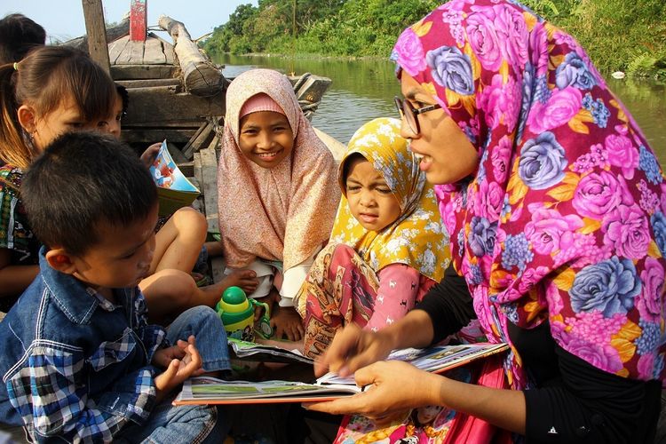 Anak-anak membaca di atas perahu menyusuri sungai hutan mangrove di Desa Percut, Kecamatan Percut Sei Tuan, Deli Serdang, Sumatera Utara. Melalui Rumah Baca Bakau, Ismail (38) dan rekan-rekannya ingin mengangkat kemampuan literasi masyarakat Desa Percut sehingga bisa mengubah tabiat warga Desa Percut yang abai menjadi lebih peka terhadap lingkungan.