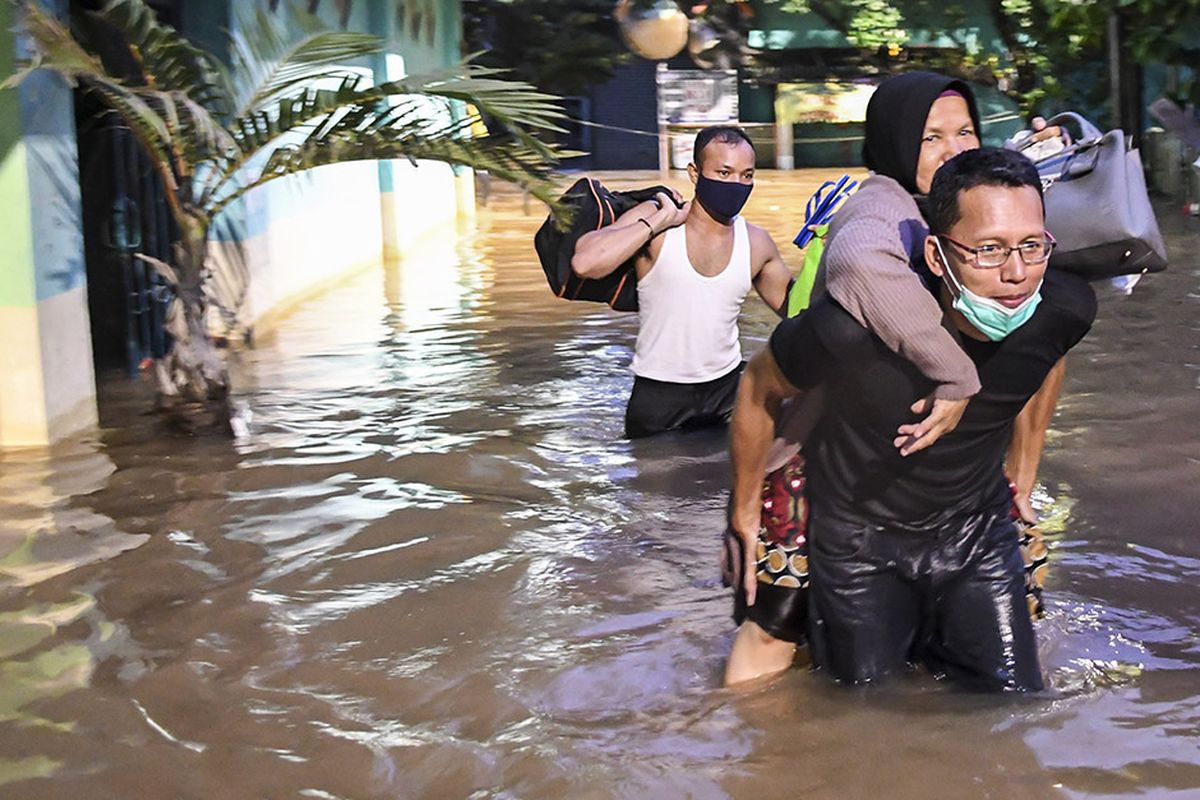 Warga berjalan melintasi banjir yang terjadi di kawasan Wijaya Timur, Petogogan, Jakarta, Sabtu (20/2/2021). Banjir yang terjadi akibat curah hujan tinggi serta drainase yang buruk membuat kawasan Petogogan banjir setinggi 1,5 meter.