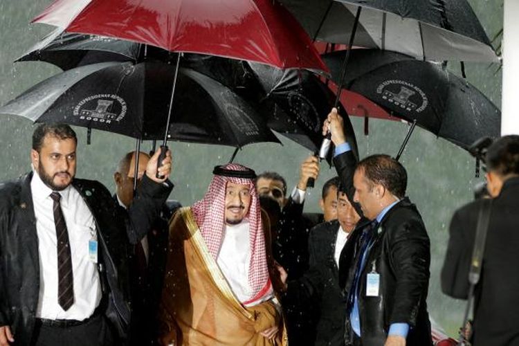Raja Arab Saudi Salman bin Abdulaziz al-Saud (tengah) dilindungi dari guyuran hujan saat akan masuk ke dalam Istana Kepresidenan Bogor, Jawa Barat, Rabu (1/3/2017).