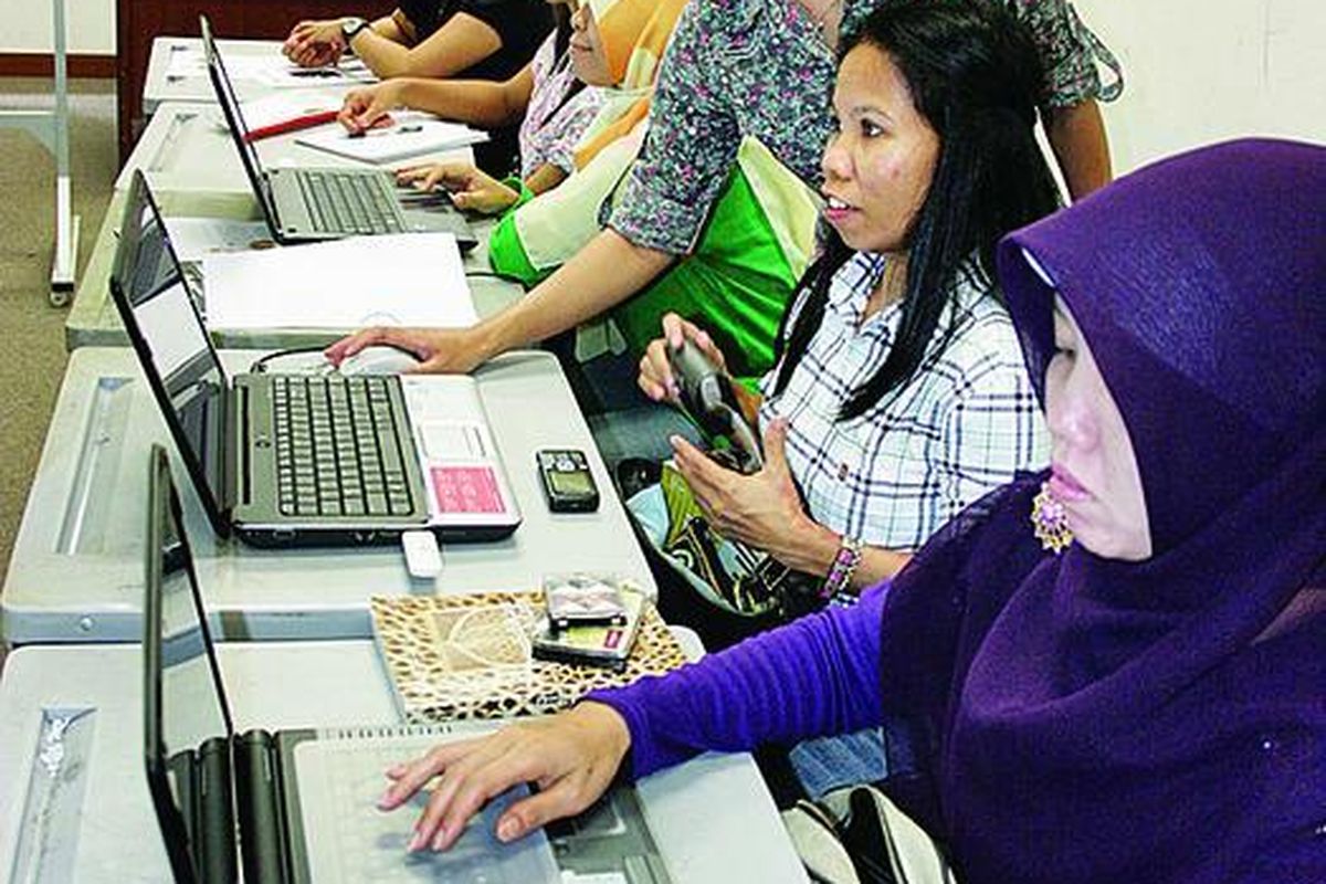 Sejumlah tenaga kerja Indonesia asyik belajar menggunakan laptop untuk mengakses bahan perkuliahan Jurusan Penerjemahan Bahasa Inggris Universitas Terbuka di gedung Sekolah Indonesia Singapura, Singapura, Minggu (23/1).
