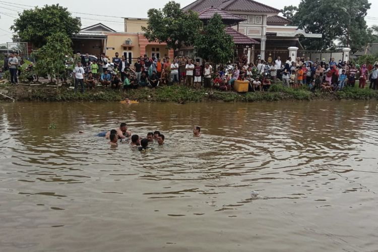 Warga saat melakukan evakuasi terhadap Atik Fitriati (53) pengemudi mobil yang nyemplung ke sungai kawasan Dekranasda Jakabaring akibat hilang kendali. Atik diketahui saat itu sedang belajar menyetir bersama suaminya yang berhasil selamat.