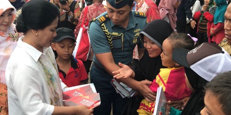 Ibu Negara Iriana Jokowi membagi-bagikan buku tulis dan syal saat baru tiba di Kecamatan Sitiung, Kabupaten Dharmasraya, Provinsi Sumatera Barat, Rabu (7/2/2018).
